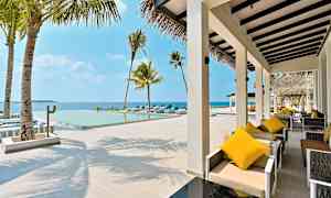 En utendørs terrasse med sittemøbler og et basseng med utsikt over havet. (AI-generert tekst)