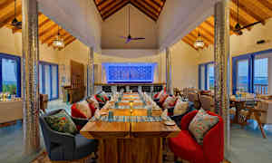 En restaurant med trebord og fargerike stoler, samt en dekorert bakvegg og store vinduer. (AI-generert tekst)