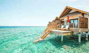 Fotografi av en bungalow på påler over turkist vann. (AI-generert tekst)