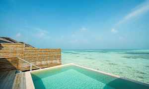 Svømmebasseng ved havet med tregjerde og klar blå himmel. (AI-generert tekst)