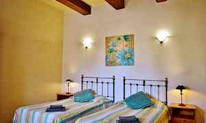 Et soverom med to enkeltsenger, vegglamper og et blått blomstermaleri på veggen. (AI-generert tekst)