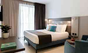 Et moderne hotellrom med en dobbeltseng, sittemøbler og interiørdetaljer. (AI-generert tekst)