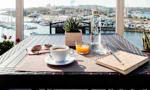 Frokostbord plassert på en terrasse med utsikt over en marina. (AI-generert tekst)