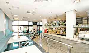 Et moderne kaféinteriør med sitteplasser og en bardisk. (AI-generert tekst)