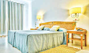 Bilde av et lyst hotellrom med en dobbeltseng og nattbord. (AI-generert tekst)