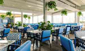 Et restaurantinteriør med blå stoler og grønne planter. (AI-generert tekst)