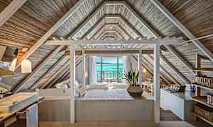 Rom med tak i trepanel og utsikt mot havet gjennom glassdører. (AI-generert tekst)