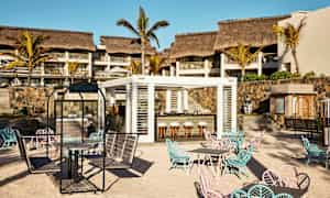 En utendørsbar med sitteplasser på en sandstrand foran et hotell. (AI-generert tekst)