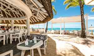 En åpen restaurant ved stranden med hvite møbler og utsikt over havet. (AI-generert tekst)