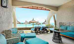 En terrasse med blå sittemøbler og utsikt mot havet med parasoller. (AI-generert tekst)