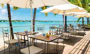 Uterestaurant ved sjøen med bord, stoler og parasoller. (AI-generert tekst)