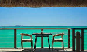 Et dekket bord med to stoler på en uteplass med sjøutsikt. (AI-generert tekst)