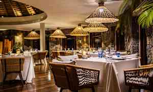 En elegant restaurant med dekkede bord og rottinglamper. (AI-generert tekst)