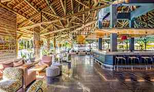 Romslig lounge med trebjelker i taket, sittegrupper og en bar. (AI-generert tekst)