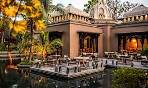 En utendørs setting med bord og stoler ved en bygning med kuppelformet tak. (AI-generert tekst)