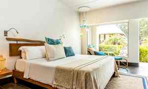 Et lyst soverom med en dobbeltseng og store vinduer ut mot en frodig hage. (AI-generert tekst)