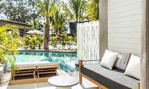 Utendørsområde med basseng, solsenger og en sofa med puter. (AI-generert tekst)