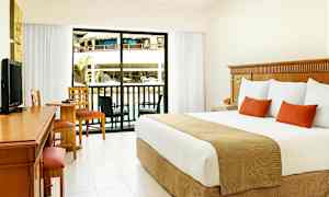 Hotellrom med stor seng, skrivebord og sittegruppe. Glassdør som åpner ut til en balkong med utsikt over bassengområde. (AI-generert tekst)