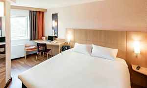 Hotellrom med en dobbeltseng, et skrivebord med en stol og et vindu. (AI-generert tekst)