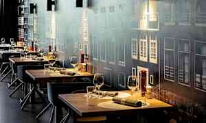 Flere dekkede restaurantbord med glass og bestikk, mot en vegg med fasademotiv. (AI-generert tekst)