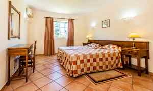 Et hotellrom med to enkeltsenger og et skrivebord ved veggen. (AI-generert tekst)