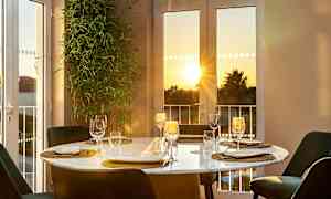 Et dekket spisebord ved vinduet med utsikt mot solnedgang. (AI-generert tekst)