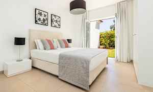 Et soverom med en dobbeltseng, nattbord og vindu med utsikt over en hage. (AI-generert tekst)