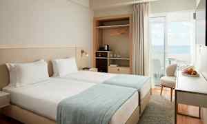 Et hotellrom med to enkeltsenger og havutsikt. (AI-generert tekst)