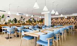 Restaurant med blå stoler og trebord, omgitt av planter. (AI-generert tekst)