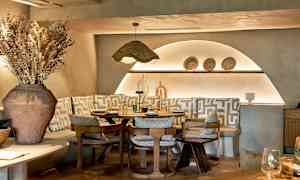 Et stilfullt restaurantbord omgitt av stoler og benker med geometriske mønstrede puter. (AI-generert tekst)