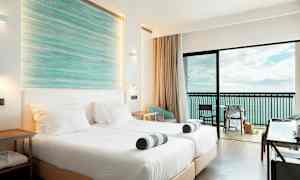 Et hotellrom med to senger, balkong og havutsikt. (AI-generert tekst)