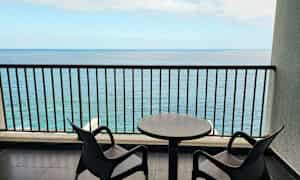 To stoler og et bord på en balkong med havutsikt. (AI-generert tekst)