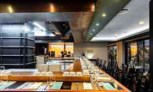 Bildet viser en moderne restaurant med borddekking og åpent kjøkken. (AI-generert tekst)