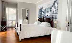 Et hotellrom med to enkeltsenger, tregulv og et stort veggmaleri. (AI-generert tekst)