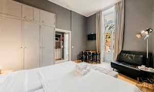 Hotellrom med seng, sofa og spisebord, store garderober samt en balkongdør. (AI-generert tekst)