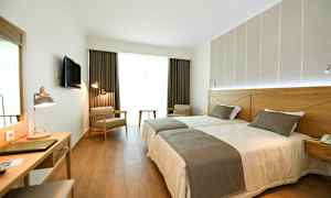 Hotellrom med to enkeltsenger, skrivebord og sitteplasser. (AI-generert tekst)