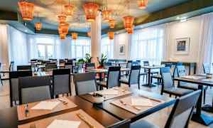 Restaurant med dekkede bord og moderne stoler, med oransje lamper i taket. (AI-generert tekst)