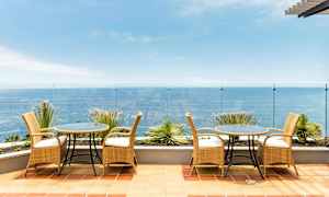 En terrasse med møbler i rotting og utsikt over havet. (AI-generert tekst)