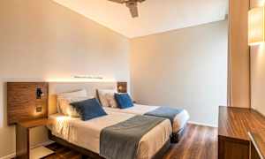 Et rom med to enkeltsenger, dekorative puter og en trebakt interiør. (AI-generert tekst)