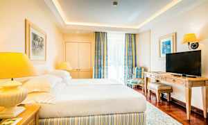 Et hotellrom med to senger, en TV og en stol. (AI-generert tekst)