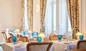 Bilde av en elegant restaurant med dekkede bord, blå glass og varm belysning. (AI-generert tekst)