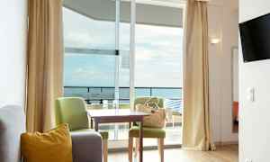 Et hotellrom med sittegruppe og utsikt mot havet. (AI-generert tekst)