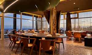 Bord og stoler i en moderne restaurant med store glassvinduer. (AI-generert tekst)