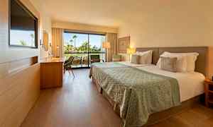 Moderne hotellrom med dobbeltseng og balkong i bakgrunnen. (AI-generert tekst)