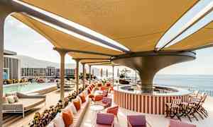 Moderne bassengområde med skyggende tak, solsenger og utsikt over havet. (AI-generert tekst)