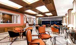 En elegant lounge med røde stoler, marmorgulv og tredetaljer i taket. (AI-generert tekst)