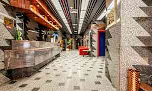 Hotellobby med marmordekor, et resepsjonsområde og røde sittemøbler. (AI-generert tekst)