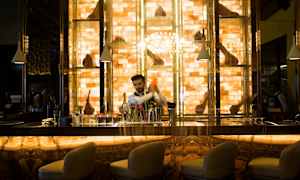 En vakkert opplyst bardisk med stoler i forgrunnen og hyller med pyntegjenstander i bakgrunnen. (AI-generert tekst)