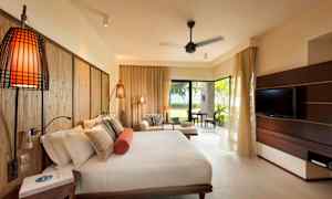 Et hotellrom med en stor seng, en sittegruppe og en TV, samt utsikt mot en frodig hage. (AI-generert tekst)