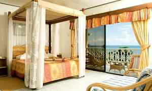 Et soverom med himmelseng og utsikt over havet fra en balkong. (AI-generert tekst)